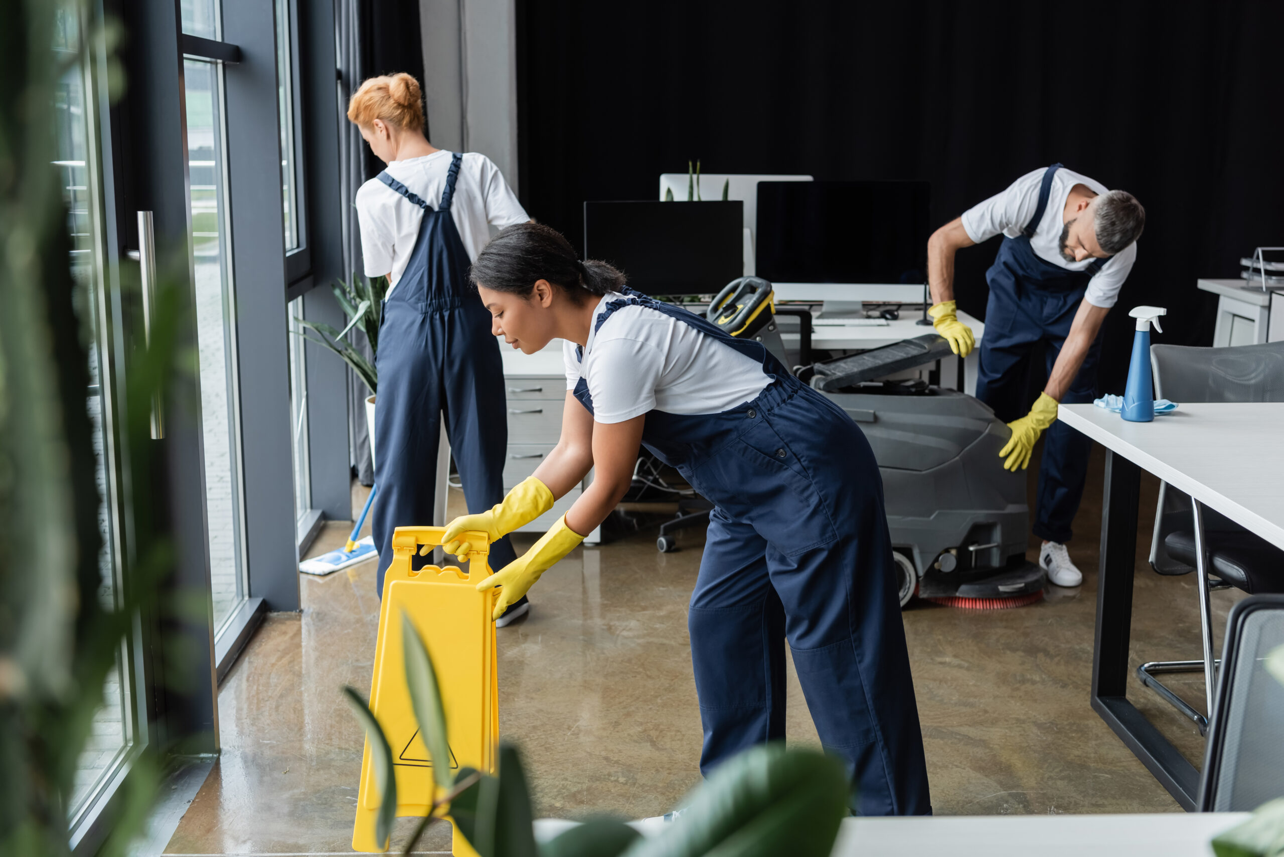 team of multiethnic and professional cleaners in uniform working in modern office